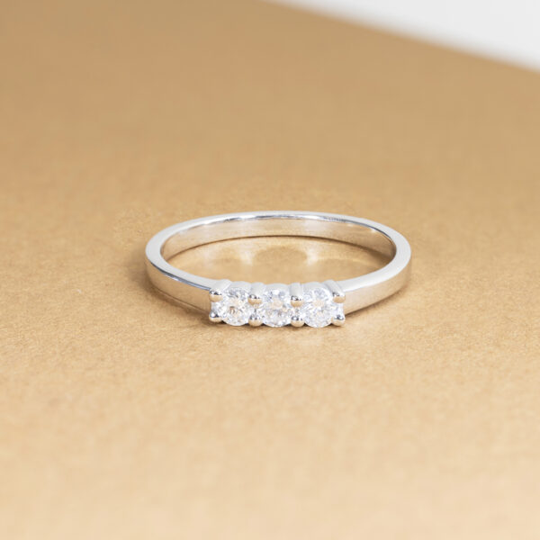 Bague en argent avec trois diamants scintillants, idéale pour une proposition ou un cadeau spécial. Ce modèle élégant et moderne met en valeur des pierres précieuses disposées en ligne, illuminant toute occasion avec une touche de sophistication et de romantisme.